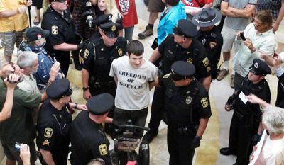 Jeremy Ryan, of Madison, is led away by Capitol police as part of a crackdown on people who gather daily in the Capitol without a permit to sing protest songs on Thursday, July 25, 2013, in Madison, Wis. (AP Photo/Scott Bauer)