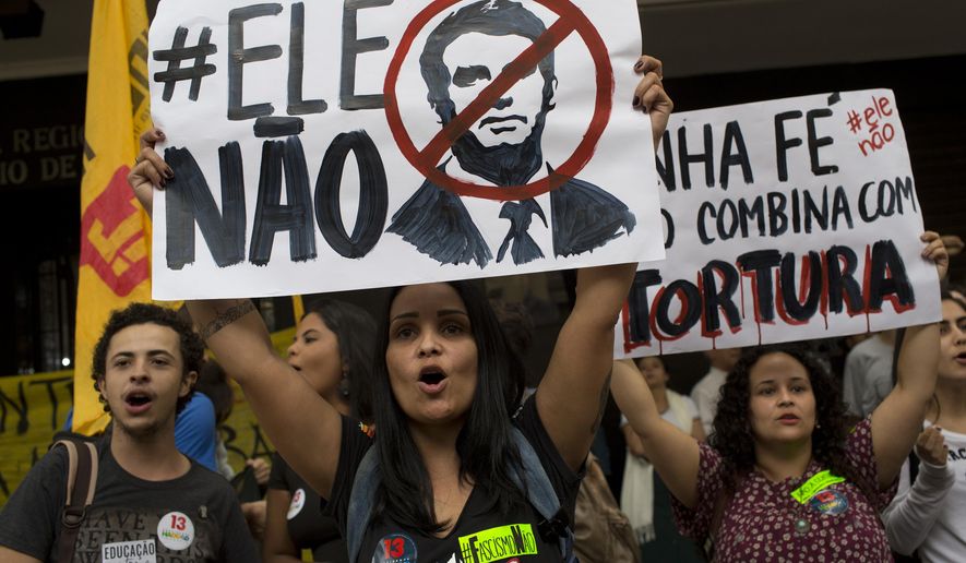 University students hold signs with message that read in Portuguese: &amp;quot;Not Him&amp;quot; and &amp;quot;My faith doesn&#x27;t go with torture&amp;quot; during a protest of an electoral court order for universities to remove banners containing &#x27;negative propaganda&#x27; against presidential frontrunner Jair Bolsonaro, in front of the Regional Electoral Tribunal in Rio de Janeiro, Brazil, Friday, Oct. 26, 2018. The Brazilian Bar Association is criticizing the order, releasing a statement that reads the court&#x27;s decision was an attempt to limit the freedom of expression of students and professors. (AP Photo/Silvia Izquierdo)