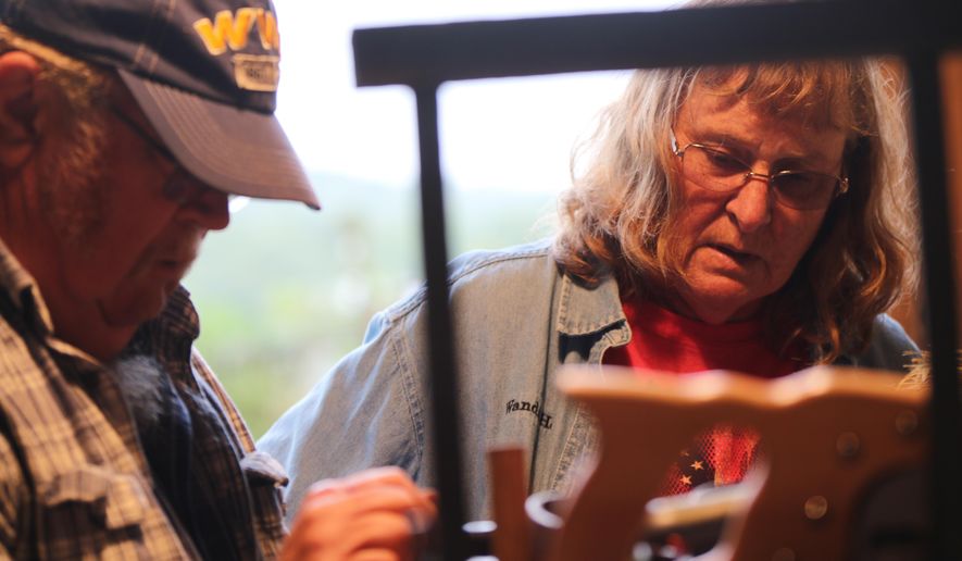 This photo taken Sept. 8, 2018, shows Wanda and Steve Hott discussing an issue with a piece of equipment at their home in Kirby, W. Va. Wanda Hott works as a professional school bus driver for Hampshire County Schools during a normal workday, but for more than a decade she’s also been a broom maker. “I got into broom making, because my sister wanted to know what I wanted for Christmas one year,” Hott said. “I needed a broom; I wanted a practical broom, and she got me a broom from Jim Shaffer.” (Daniel Walker/West Virginia Public Broadcasting via AP)