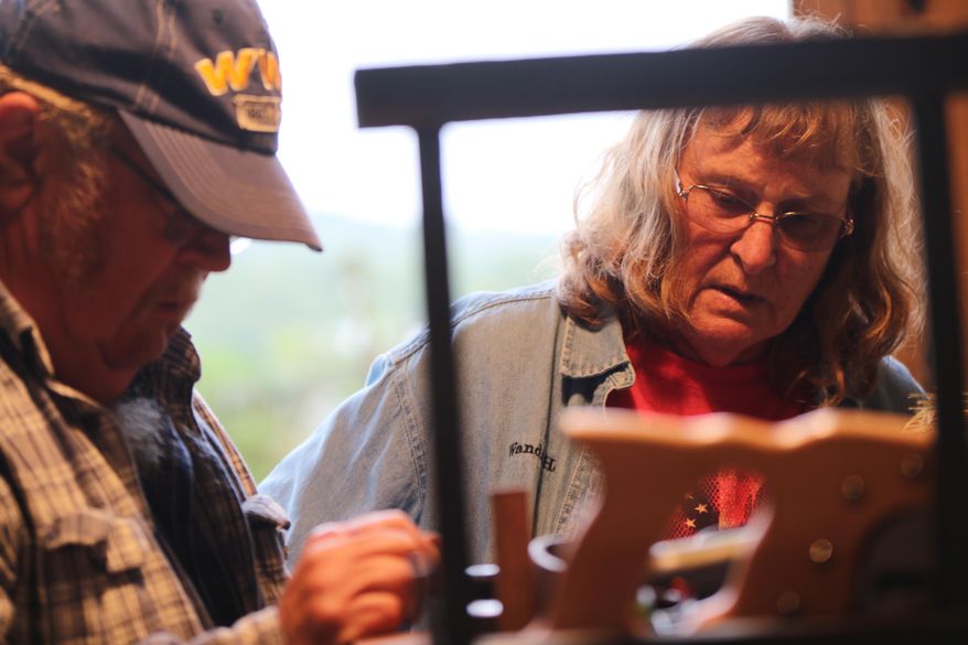This photo taken Sept. 8, 2018, shows Wanda and Steve Hott discussing an issue with a piece of equipment at their home in Kirby, W. Va. Wanda Hott works as a professional school bus driver for Hampshire County Schools during a normal workday, but for more than a decade she’s also been a broom maker. “I got into broom making, because my sister wanted to know what I wanted for Christmas one year,” Hott said. “I needed a broom; I wanted a practical broom, and she got me a broom from Jim Shaffer.” (Daniel Walker/West Virginia Public Broadcasting via AP)