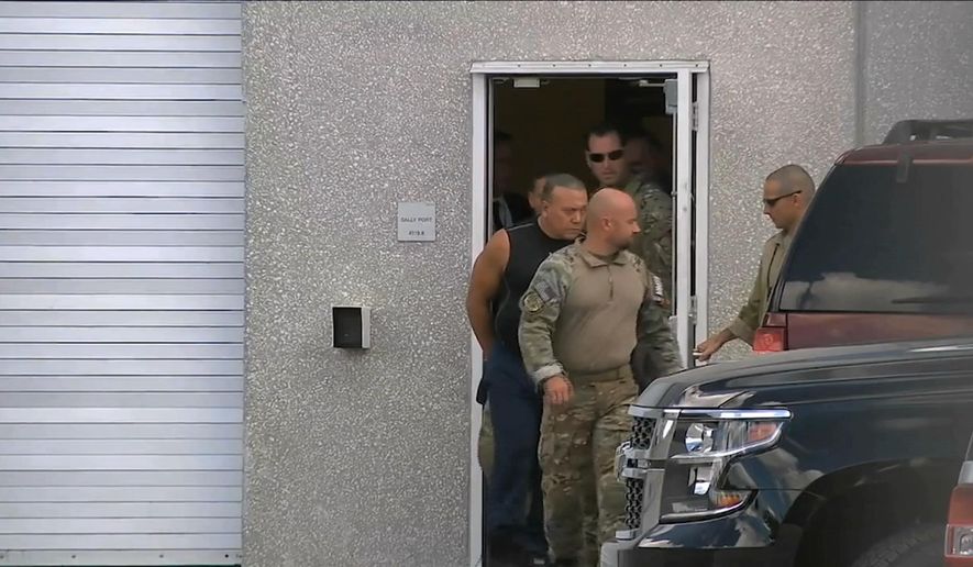 This frame grab from video provided by WPLG-TV shows FBI agents escorting Cesar Sayoc, in sleeveless shirt, in Miramar, Fla., on Friday, Oct. 26, 2018. Sayoc is an amateur body builder and former male stripper, a loner with a long arrest record who showed little interest in politics until Donald Trump came along. On Friday, he was identified by authorities as the Florida man who put pipe bombs in small manila envelopes, affixed six stamps and sent them to some of Donald Trump's most prominent critics. (WPLG-TV via AP)