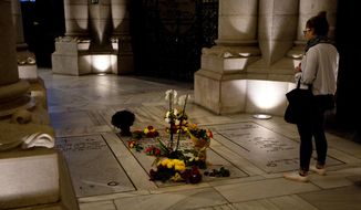 A woman stops to look at the Franco family burial space adorned with flowers in the Almudena Crypt, a cavernous late-19th century Catholic temple under Madrid&#39;s Almudena cathedral, in central Madrid, Spain, Thursday Oct. 25, 2018. Hundreds of protesters in Madrid are urging government and Catholic church authorities to prevent the remains of the country’s 20th century dictator from ending in the city’s cathedral. Spain’s center-left government has promised to exhume this year Gen. Francisco Franco from a glorifying mausoleum, but the late dictator’s heirs have defied the plans by proposing for his remains to be relocated to a family crypt under the cathedral.(AP Photo/Paul White)