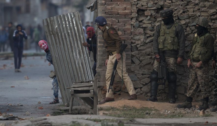 In this Oct. 19, 2018, photo, Kashmiri protesters take cover behind a tin sheet as they clash with Indian security forces in Srinagar, India. Government forces fired tear gas and pellets on Kashmiris who gathered after Friday afternoon prayers on a protest call given by separatists against the killing two rebels and a civilian during a gunbattle in Srinagar on Wednesday. (AP Photo/Dar Yasin, File)