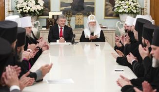 Ukrainian President Petro Poroshenko, center left, and Patriarch Filaret, head of the Ukrainian Orthodox Church of the Kiev Patriarchate and clerics during their meeting in Kiev, Ukraine, Sunday, Oct. 21, 2018. The Istanbul-based Ecumenical Patriarchate says it will move forward with its decision to grant Ukrainian clerics independence from the Russian Orthodox Church. (Mikhail Palinchak, Presidential Press Service Pool Photo via AP)
