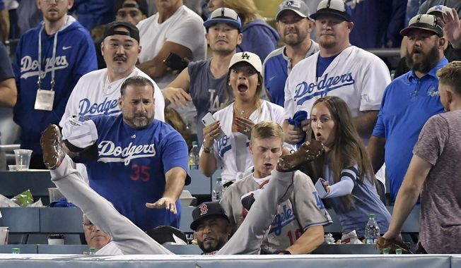 Boston Red Sox third baseman Eduardo Nunez falls into the stands after catching a foul ball hit by Los Angeles Dodgers' Cody Bellinger during the 13th inning in Game 3 of the World Series baseball game on Friday, Oct. 26, 2018, in Los Angeles. (AP Photo/Mark J. Terrill)