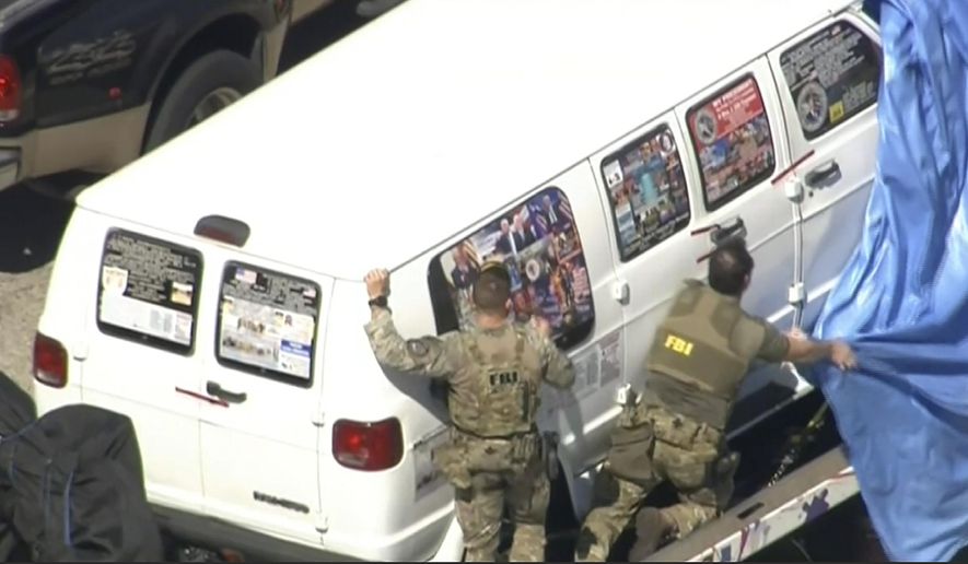 This frame grab from video provided by WPLG-TV shows FBI agents covering a van after the tarp fell off as it was transported from Plantation, Fla., on Friday, Oct. 26, 2018, that federal agents and police officers have been examining in connection with package bombs that were sent to high-profile critics of President Donald Trump. The van has several stickers on the windows, including American flags, decals with logos and text. (WPLG-TV via AP)