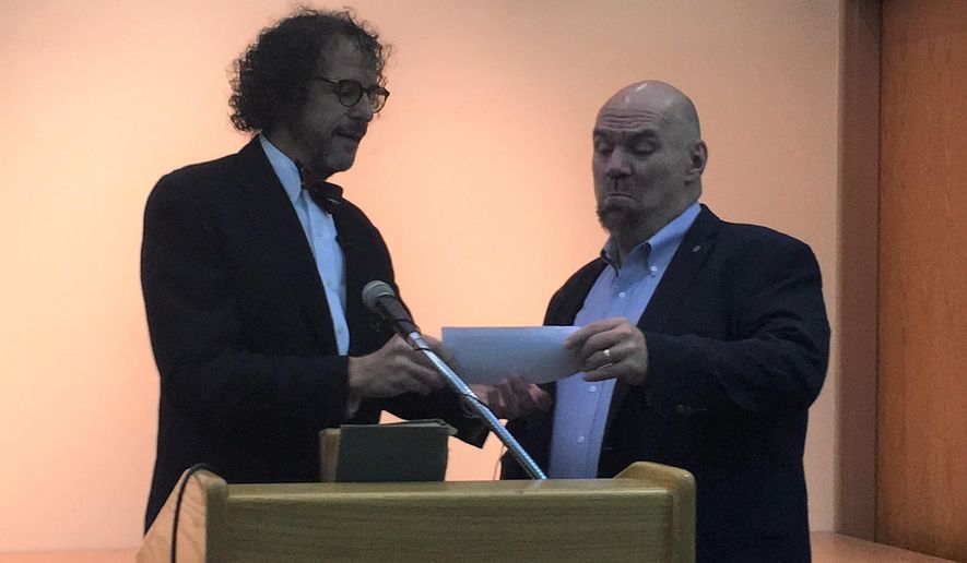 In this undated photo Robert Stroud, left, presents a check to Shreve Memorial Library Executive Director John Tuggle, a donation to the library after returning a book that was 84 years overdue. (Sarah Crawford/The Shreveport Times via AP)