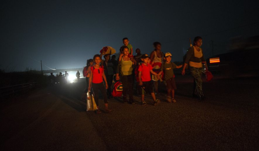 A family walks among other Central American migrants in a caravan of several thousand that is slowly making its way toward the U.S. border, outside Arriaga, Mexico, before dawn on Saturday, Oct. 27, 2018. Many migrants said they felt safer traveling and sleeping with thousands of strangers in unknown towns than hiring a smuggler or trying to make the trip alone. (AP Photo/Rodrigo Abd)