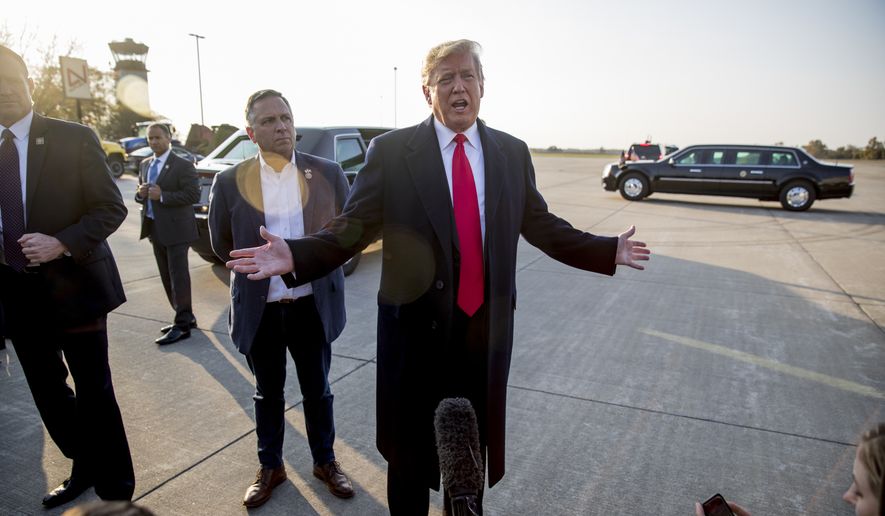 President Donald Trump, accompanied by Rep. Mike Bost, R-Ill., center left, speaks to reporters about a shooting at a Pittsburgh synagogue as he arrives at Southern Illinois Airport in Murphysboro, Ill., Saturday, Oct. 27, 2018, for a rally. (AP Photo/Andrew Harnik)