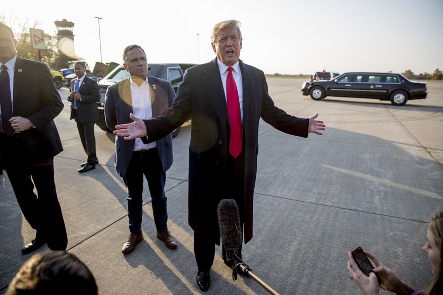 President Donald Trump, accompanied by Rep. Mike Bost, R-Ill., center left, speaks to reporters about a shooting at a Pittsburgh synagogue as he arrives at Southern Illinois Airport in Murphysboro, Ill., Saturday, Oct. 27, 2018, for a rally. (AP Photo/Andrew Harnik)