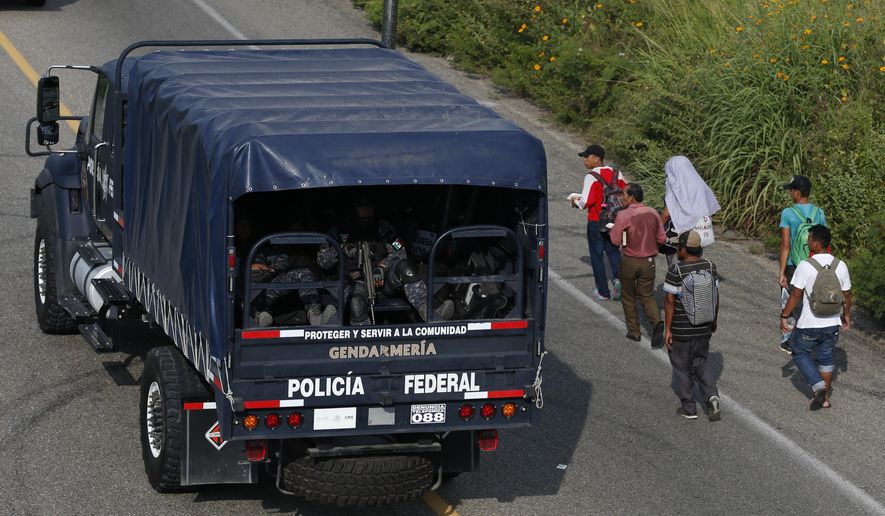 Mexican federal police drive away past Central Americans continuing on their journey, after police removed the blockade that had briefly halted a thousands-strong migrant caravan outside the town of Arriaga, Chiapas state, Mexico, Saturday, Oct. 27, 2018. Hundreds of Mexican federal officers carrying plastic shields had blocked the caravan from advancing toward the United States, after several thousand of the migrants turned down the chance to apply for refugee status and obtain a Mexican offer of benefits. (AP Photo/Rebecca Blackwell)