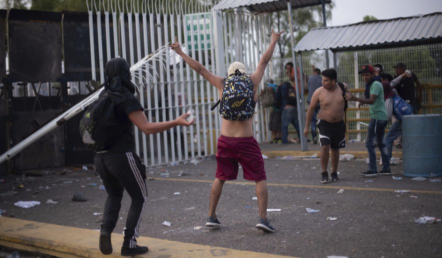 A Central American migrant taunts Mexican authorities at a border bridge crossing connecting Guatemala and Mexico, in Tecun Uman, Guatemala, Sunday, Oct. 28, 2018. A new group of migrants, who called themselves a second caravan, gathered on a bridge after forcing their way through a gate at the Guatemalan end. (AP Photo/Santiago Billy)