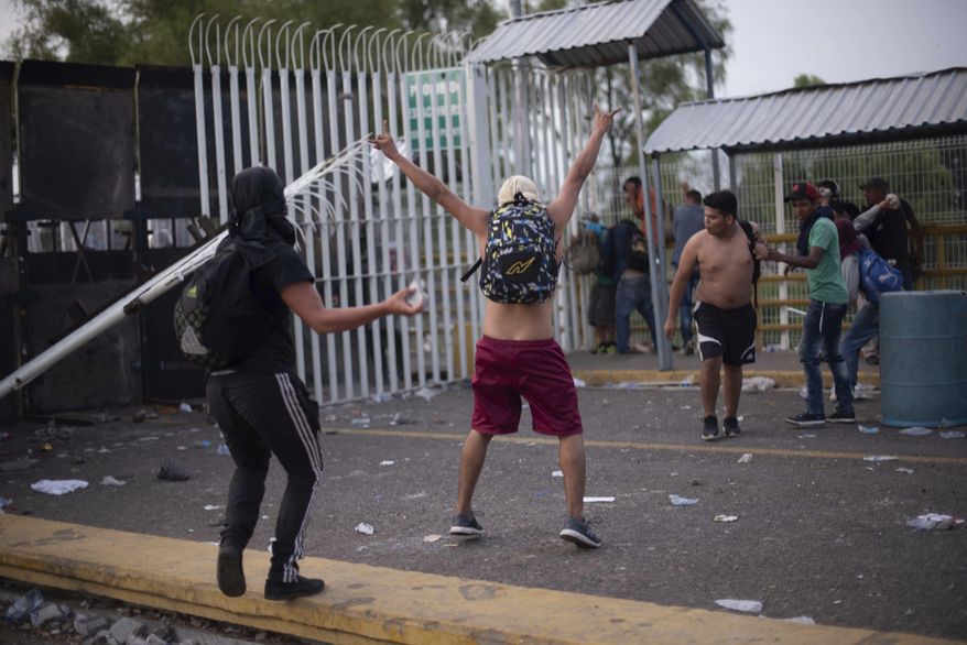 A Central American migrant taunts Mexican authorities at a border bridge crossing connecting Guatemala and Mexico, in Tecun Uman, Guatemala, Sunday, Oct. 28, 2018. A new group of migrants, who called themselves a second caravan, gathered on a bridge after forcing their way through a gate at the Guatemalan end. (AP Photo/Santiago Billy)