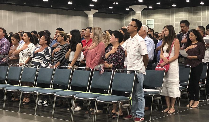 In this Sept. 18, 2018 photo new American citizens stand during a naturalization ceremony in Los Angeles. More than 700,000 immigrants are waiting on their applications to become U.S. citizens, a process that in many parts of the country now takes a year or more. The number of aspiring Americans surged during 2016, jumping 27 percent from a year ago as Donald Trump made cracking down on immigration a central point of his presidential campaign. (AP Photo/Amy Taxin)