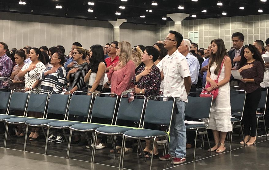In this Sept. 18, 2018 photo new American citizens stand during a naturalization ceremony in Los Angeles. More than 700,000 immigrants are waiting on their applications to become U.S. citizens, a process that in many parts of the country now takes a year or more. The number of aspiring Americans surged during 2016, jumping 27 percent from a year ago as Donald Trump made cracking down on immigration a central point of his presidential campaign. (AP Photo/Amy Taxin)