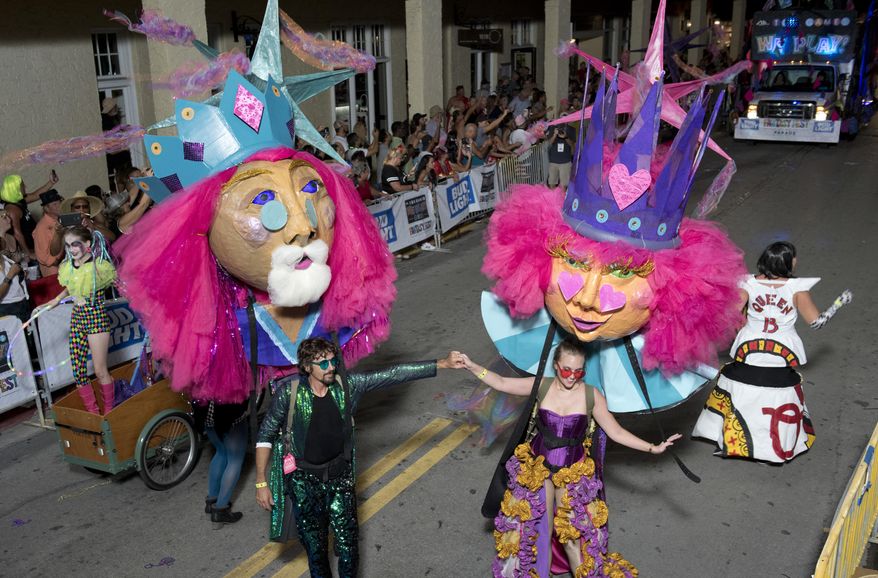 In this Saturday, Oct. 27, 2018, photo provided by the Florida Keys News Bureau, revelers supporting king and queen puppets make their way up Duval Street during the Fantasy Fest Parade in Key West, Fla. The extravaganza was the highlight event of the 10-day Fantasy Fest costuming and masking festival that ends Sunday, Oct. 28. (Rob O'Neal/Florida Key News Bureau via AP)