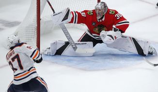 Edmonton Oilers&#39; Connor McDavid, left, scores the winning goal against Chicago Blackhawks&#39; Cam Ward during overtime of an NHL hockey game Sunday, Oct. 28, 2018, in Chicago. (AP Photo/Jim Young)