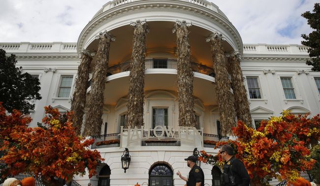 Secret Service police walk past the South Portico of the White House decorated for Halloween, Sunday, Oct. 28, 2018, in Washington. President Donald Trump and first lady Melania Trump will greet children this afternoon during a Halloween event at the White House. (AP Photo/Jacquelyn Martin)