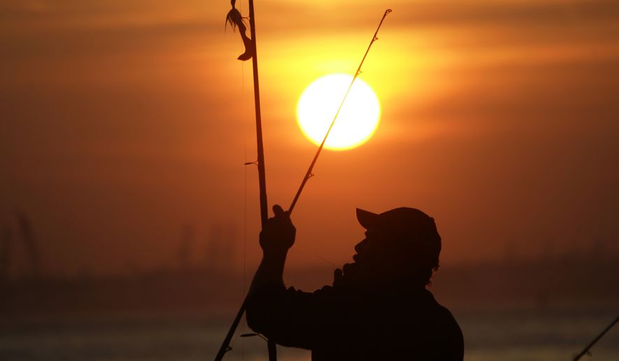 A man works with his fishing rod as the sun sets on the waterfront in the Red Hook section of the borough of Brooklyn  on Thursday, March 22, 2012 in New York. (AP Photo/Peter Morgan)