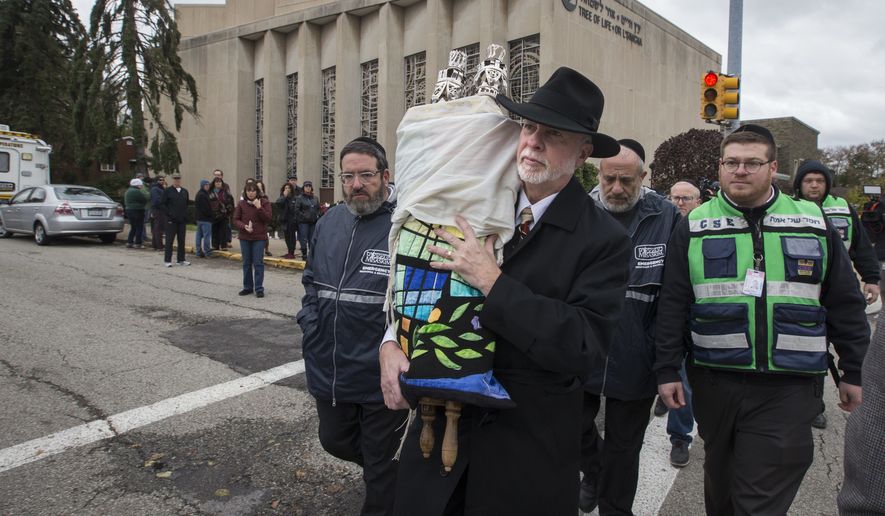 Rabbi Jeffrey Myers, center, of Tree of Life Synagogue carries their Torah to be stored elsewhere in Pittsburgh on Monday, October 29, 2018. The man accused in the Pittsburgh synagogue massacre appeared briefly in federal court in a wheelchair and handcuffs Monday to face charges he killed 11 people in what is believed to be the deadliest attack on Jews in U.S. history. (Charles Fox/The Philadelphia Inquirer via AP)