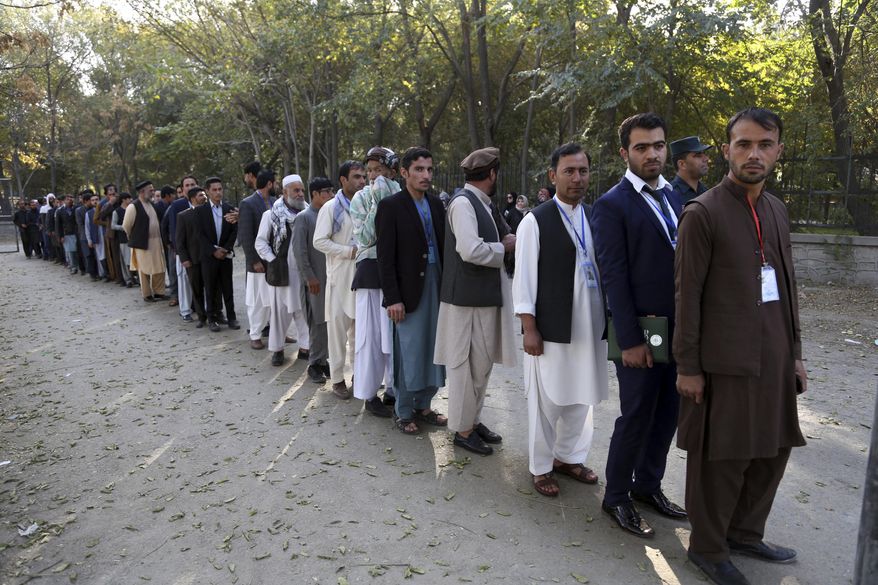 FILE - In this Saturday, Oct. 20, 2018 file photo, Afghan men line up to cast their votes, outside a polling station during the Parliamentary election in Kabul, Afghanistan. A new survey released last Friday, has found record lows in how Afghans rate their chances for a better life. Afghans worry more, laugh less and are the most pessimistic about their future than any other country surveyed by Gallup since 2006, when the organization first began to measure how good people feel about themselves, their lives and their prospects. (AP Photo/Rahmat Gul, File)
