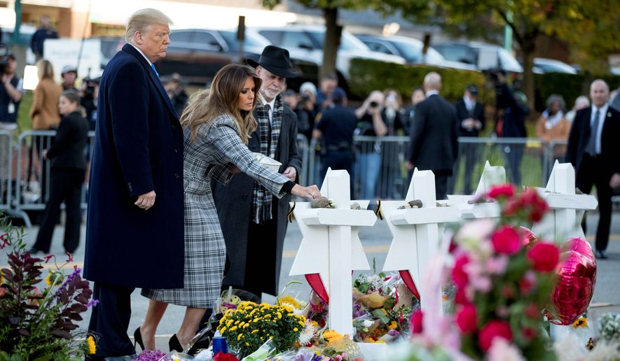First lady Melania Trump, accompanied by President Donald Trump, and Tree of Life Rabbi Jeffrey Myers, right, puts down a white flower at a memorial for those killed at the Tree of Life Synagogue in Pittsburgh, Tuesday, Oct. 30, 2018. (AP Photo/Andrew Harnik)