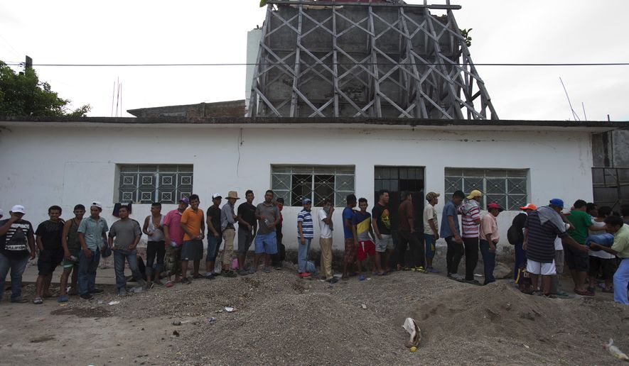 Migrants line up to receive food handouts in front of the backside of a church heavily damaged in a Sept. 7, 2017 earthquake, as a thousands-strong caravan of Central Americans hoping to reach the U.S. border stops for the night in Niltepec, Oaxaca state, Mexico, Monday, Oct. 29, 2018. As the caravan resumed its slow advance Monday, still at least 1000 miles or farther from the U.S., the Pentagon announced it would send 5,200 active-duty troops to "harden" the border. (AP Photo/Rebecca Blackwell)