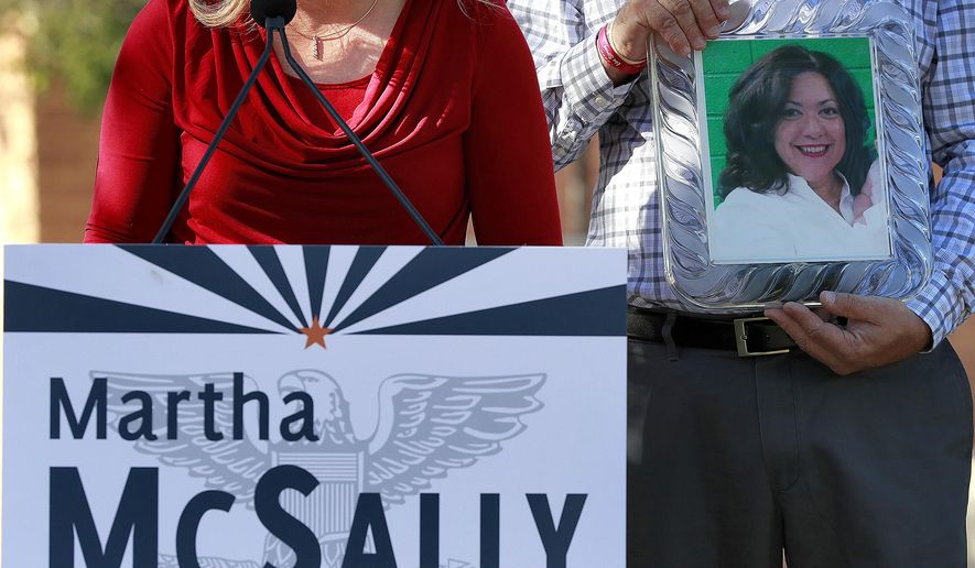 A photograph of Corine Turner, who was murdered by an immigrant living in the United States illegally, is displayed as Carrie Utz speaks, Tuesday, Oct. 30, 2018, in Mesa, Ariz. Utz was speaking at a news conference held by U.S. Rep. Martha McSally, R-Ariz., who is running for the U.S. Senate. McSally was drawing attention to "angel families", people who lost loved ones at the hands of immigrants living the the United States illegally. (AP Photo/Matt York)