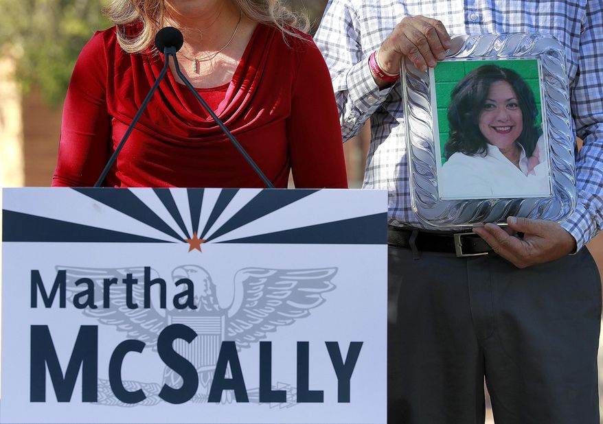 A photograph of Corine Turner, who was murdered by an immigrant living in the United States illegally, is displayed as Carrie Utz speaks, Tuesday, Oct. 30, 2018, in Mesa, Ariz. Utz was speaking at a news conference held by U.S. Rep. Martha McSally, R-Ariz., who is running for the U.S. Senate. McSally was drawing attention to "angel families", people who lost loved ones at the hands of immigrants living the the United States illegally. (AP Photo/Matt York)