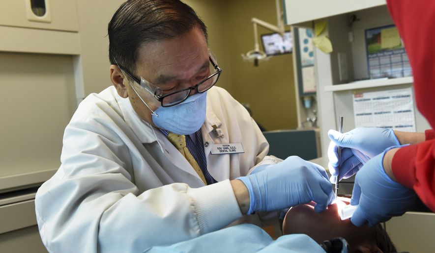 In this Oct. 18, 2018, photo, dentist Kou Vang works on a patient in his St. Paul, Minn. office. Vang, 63, didn&#x27;t get around to dentistry until he was in his 40s. He was told he was the first Hmong to go into dentistry in Minnesota, and probably the first grandfather to graduate from his program. That&#x27;s because Vang&#x27;s life took him the long way, through war, prison camp, destitution, immigration and a lot of hard work. (Scott Takushi/Pioneer Press via AP)