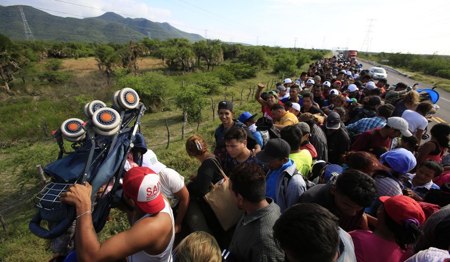 A man holds up a stroller as hundreds of migrants hitching a ride accommodate themselves on the back of truck, between Niltepec and Juchitan, Mexico, Tuesday, Oct. 30, 2018. The group is already significantly diminished from its estimated peak at over 7,000-strong. (AP Photo/Rebecca Blackwell)