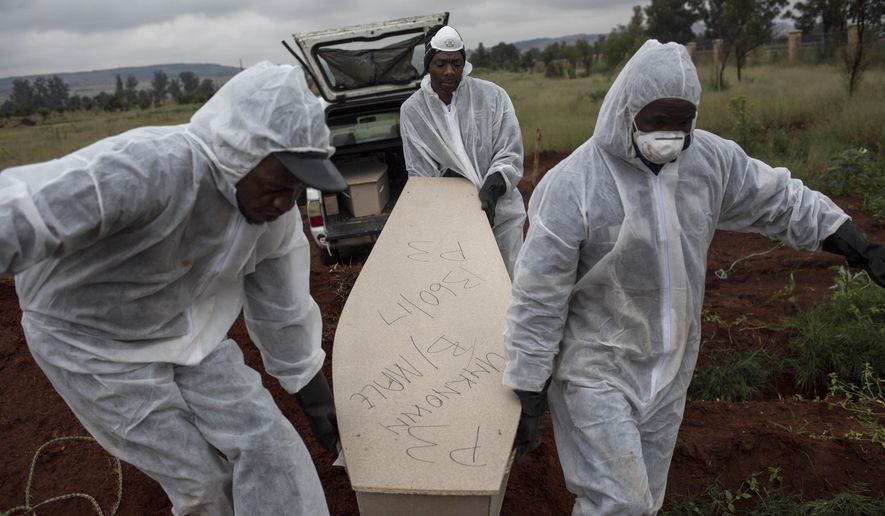 In this Thursday, April 12, 2018, file photo, mortuary workers carry the coffin of an unidentified man for burial at a cemetery outside Johannesburg. At least five bodies of unidentified people are buried on top of each other in each grave. (AP Photo/Bram Janssen)