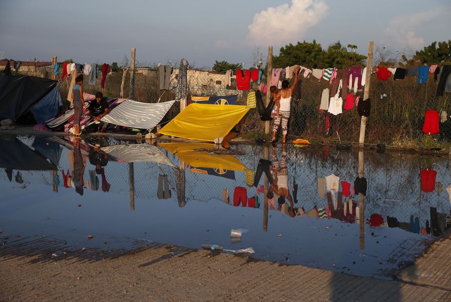 Water is left behind after migrants took showers with donated water brought in by truck, in an area where migrants are camping and doing laundry, as a thousands-strong caravan of Central Americans hoping to reach the U.S. border takes a rest day in Juchitan, Oaxaca state, Mexico, Wednesday, Oct. 31, 2018. Thousands of weary Central American migrants in a caravan rested Wednesday in southern Mexico while their representatives tried to negotiate transportation hundreds of miles ahead to the capital, but by evening there was bad news: they'd be walking again the next day. (AP Photo/Rebecca Blackwell)