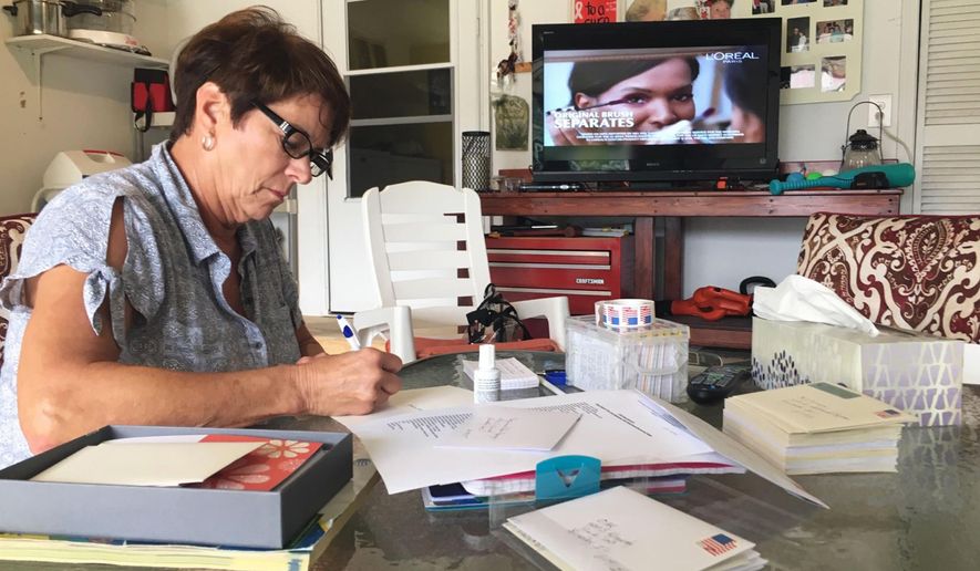 In this Oct. 23, 2018 photo, Shelly Link writes thank-you cards to local businesses and residents who sponsored a golf tournament last month to help raise money for brain cancer research at her home in Bourbonnais, Ill. Her husband, Mike, died of brain cancer in 2015. (David Giuliani/The Daily Journal via AP)