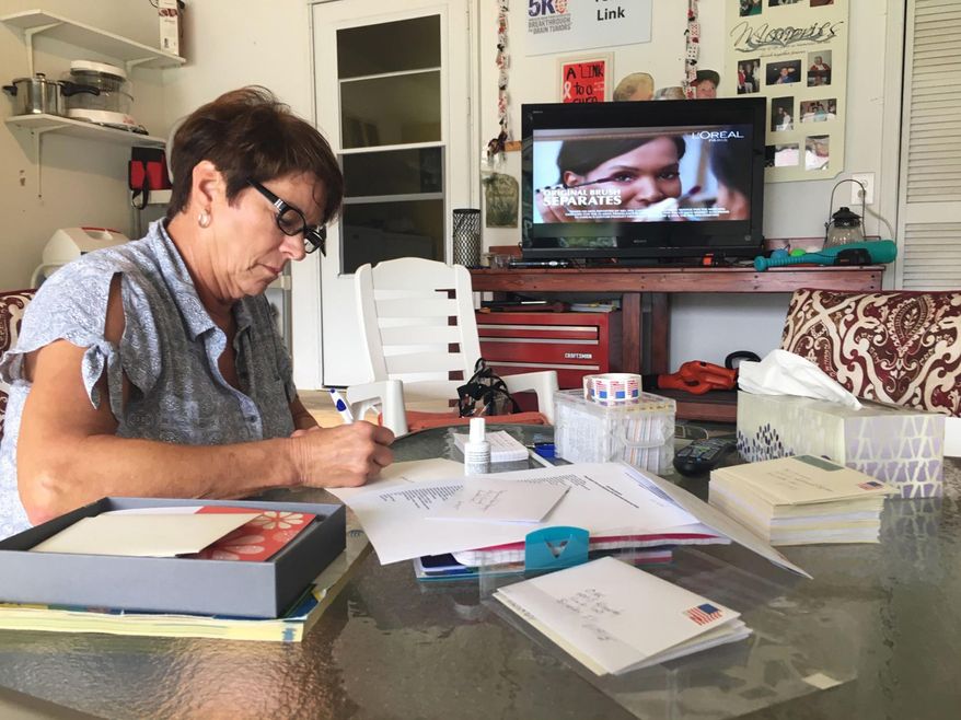 In this Oct. 23, 2018 photo, Shelly Link writes thank-you cards to local businesses and residents who sponsored a golf tournament last month to help raise money for brain cancer research at her home in Bourbonnais, Ill. Her husband, Mike, died of brain cancer in 2015. (David Giuliani/The Daily Journal via AP)
