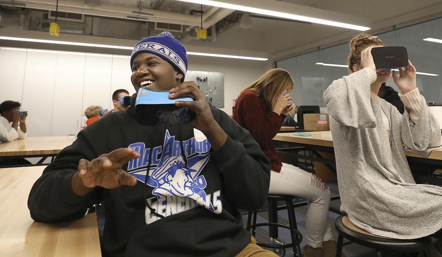 In this Oct. 13, 2018 photo, MacArthur High School student Antwone Brown reacts while taking a virtual field trip through the solar system along with Rochester High School student Abbey Conner, middle, Peoria Christian High School student Madison Fisher, far right, and other students attending the Tomorrow's Teachers conference in the New Technologies Studio at Millikin University In Decatur, Ill. (Jim Bowling/Herald & Review via AP)/