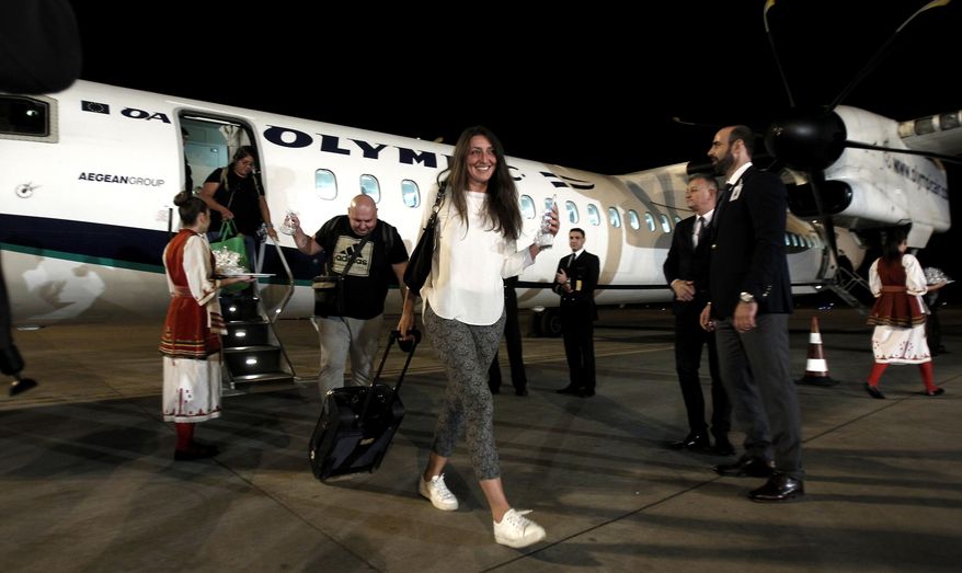 Passengers who get off an Aegean Airlines plane are welcomed with cookies, after landing at Skopje International Airport, Macedonia, Thursday, Nov. 1, 2018. Direct flights between Macedonia and Greece are set to resume after more than a decade, amid a thaw in relations following a deal to rename Macedonia "North Macedonia." (AP Photo/Boris Grdanoski)