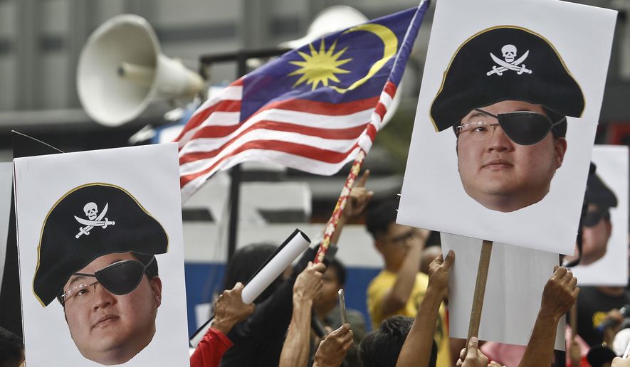 FILE - In this April 14, 2018, file photo, protesters hold portraits of Jho Low illustrated as a pirate during a protest in Kuala Lumpur, Malaysia. The United States Justice Department on Thursday charged the fugitive Malaysian financier in a money laundering and bribery scheme that pilfered billions of dollars from a Malaysian investment fund created to promote economic development projects in that country. The three-count indictment charges Low Taek Jho, who is also known as Jho Low, with misappropriating money from the state-owned fund and using it for bribes and kickbacks to foreign officials, to pay for luxury real estate, art and jewelry in the United States and to fund Hollywood movies, including &amp;quot;The Wolf of Wall Street.&amp;quot; (AP Photo/Sadiq Asyraf, File)