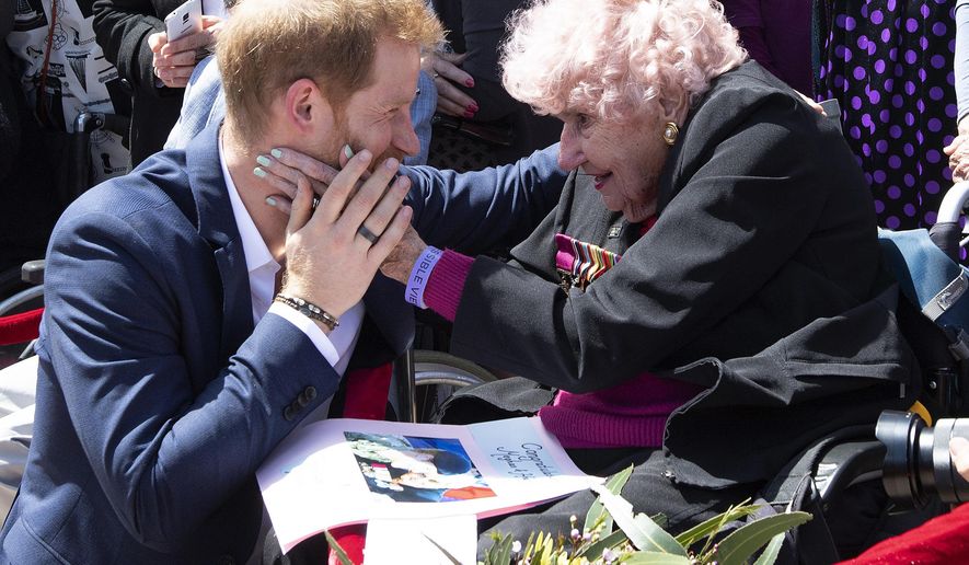 FILE- In this Oct. 16, 2018 file photo, Britain's Prince Harry is embraced by 97-year-old Dafney Dunne during a walk about outside the Opera House in Sydney, Australia. Prince Harry and his wife Meghan are on a 16-day tour of Australia and the South Pacific. (Paul Edwards/Pool via AP, File)