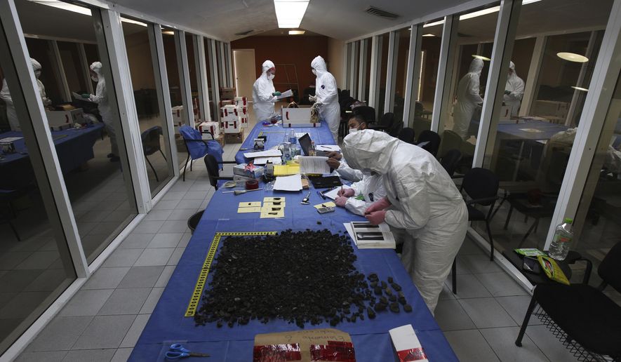 In this March 23, 2018 photo, an Argentine forensic anthropology team arrange burned fragments at a lab in Cuauhtemoc, Mexico. The fragments are among the remains of tens of thousands of people who have disappeared in Mexico's long and bloody drug war. (AP Photo/Marco Ugarte)
