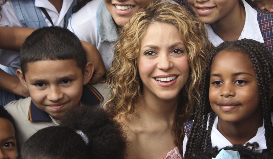 Colombian pop star Shakira posses with children after laying the cornerstone for a school her Barefoot Foundation will build in the Aranjuez neighborhood of Cartagena, Colombia, Friday, Nov. 2, 2018. (AP Photo/Pedro Mendoza)
