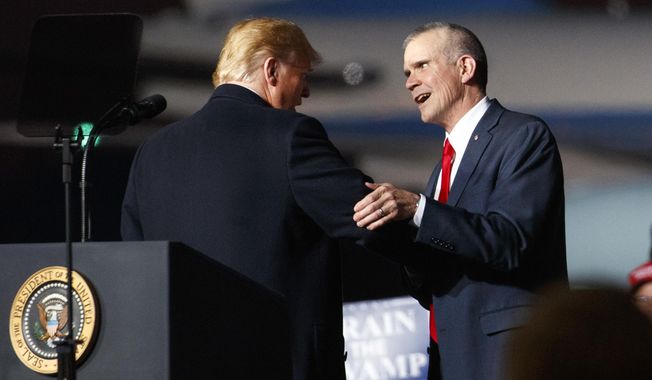 FILE - In this Oct. 18, 2018 file photo President Donald Trump and Montana State Auditor Matt Rosendale, who is running against Sen. Jon Tester, D-Mont., shake hands during a campaign rally at Minuteman Aviation Hangar in Missoula, Mont. Rosendale has President Donald Trump and other big-name Republicans surrounding him on the campaign trail. (AP Photo/Carolyn Kaster,File)