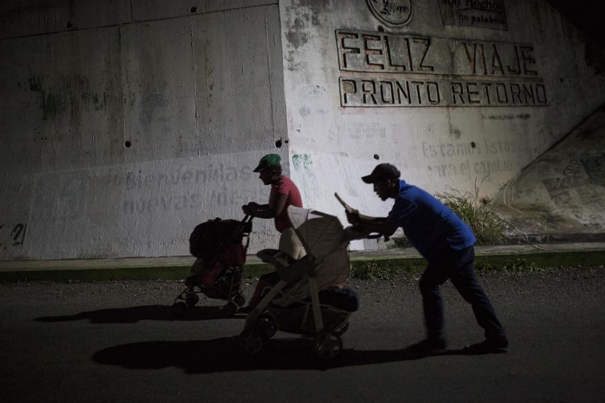Joel Eduardo Espinar, foreground, and his wife, Yamilet Hernandez, push baby strollers as they start early in the morning towards the next town Arriaga from Pijijiapan, Mexico, on Oct. 26, 2018. Two weeks earlier, the family had fled Honduras and joined the migrant caravan of Central Americans heading north. (AP Photo/Rodrigo Abd)