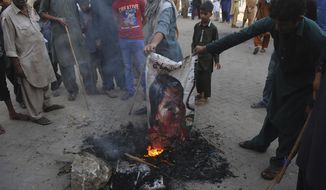 Pakistani protesters burn a poster image of Christian woman Asia Bibi, who has spent eight-years on death row accused of blasphemy and acquitted by a Supreme Court, in Hyderabad, Pakistan, Thursday, Nov. 1, 2018. Bibi plans to leave the country, her family said Thursday, as Islamists mounted rallies demanding Bibi be publicly hanged, and also called for the killing of the three judges, including Chief Justice Mian Saqib Nisar, who acquitted Bibi. (AP Photo/Pervez Masih