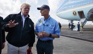 FILE- This Oct. 15, 2018 file photo shows Gov. Rick Scott, listening to President Donald Trump at Eglin Air Force Base, Fla., to visit areas affected by Hurricane Michael. Scott is challenging incumbent Democrat, Sen. Bill Nelson. (AP Photo/Evan Vucci)
