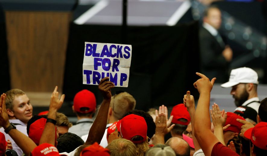 A man raises a sign &quot;Blacks For Trump&quot; as President Trump speaks on June 27 in Fargo, North Dakota. (Associated Press)
