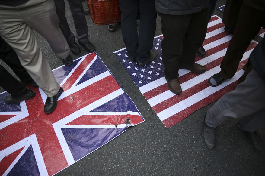 Representations of the U.S. and British flags are walked on by demonstrators during an annual rally in front of the former U.S. Embassy in Tehran, Iran, on Sunday, Nov. 4, 2018, to mark the 39th anniversary of the seizure of the embassy by militant Iranian students. Thousands of Iranians rallied in Tehran on Sunday to mark the anniversary as Washington restored all sanctions lifted under the nuclear deal. (AP Photo/Vahid Salemi)