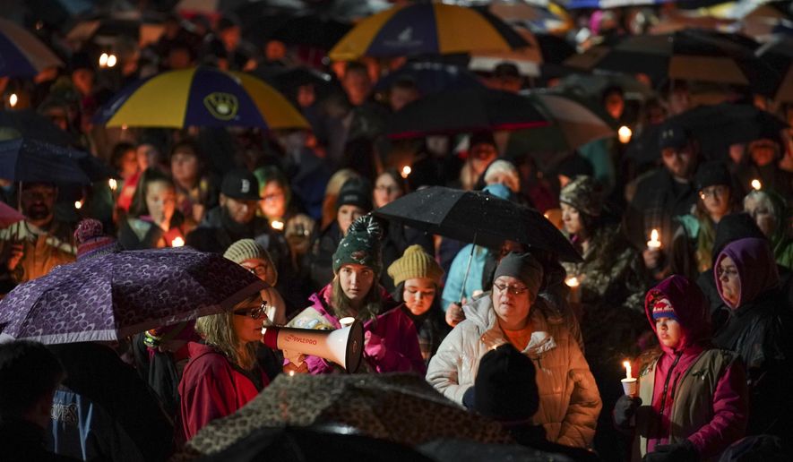 Sherri Jasper, a Girl Scout board member and counselor at Halmstad Elementary School, leads the program for a candlelight vigil at the school in Chippewa Falls, Wis., Sunday evening, Nov. 4, 2018. The western Wisconsin community on Sunday was grieving the deaths of three Girl Scouts and a parent who were collecting trash Saturday along a rural highway when police say a pickup truck veered off the road and hit them before speeding away. The 21-year-old driver, Colten Treu of Chippewa Falls, sped off but later surrendered. He will be charged with four counts of homicide, Lake Hallie police Sgt. Daniel Sokup said. (Jeff Wheeler/Star Tribune via AP)