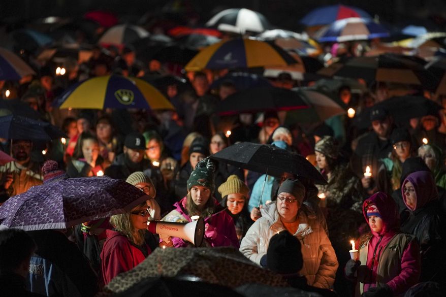 Sherri Jasper, a Girl Scout board member and counselor at Halmstad Elementary School, leads the program for a candlelight vigil at the school in Chippewa Falls, Wis., Sunday evening, Nov. 4, 2018. The western Wisconsin community on Sunday was grieving the deaths of three Girl Scouts and a parent who were collecting trash Saturday along a rural highway when police say a pickup truck veered off the road and hit them before speeding away. The 21-year-old driver, Colten Treu of Chippewa Falls, sped off but later surrendered. He will be charged with four counts of homicide, Lake Hallie police Sgt. Daniel Sokup said. (Jeff Wheeler/Star Tribune via AP)