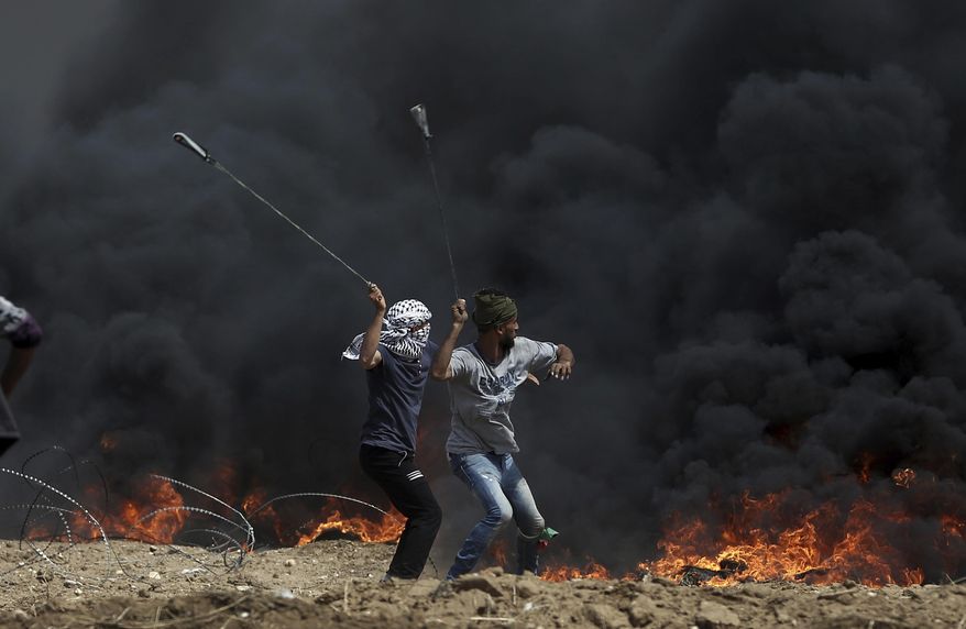 FILE - In this April 27, 2018 file photo, Palestinian protesters hurl stones at Israeli troops during a protest at the Gaza Strip's border with Israel. President Donald Trump’s assertion that stones thrown by Latin American protesters at American troops should be treated as “rifles” has sparked debate about the appropriate response to rock throwing crowds -- particularly after Nigerian troops appeared to use his comments as justification for a deadly crackdown on demonstrators over the weekend. From the Gaza Strip to Africa to Europe, security forces have long dealt with stone throwers, albeit in very different ways. (AP Photo/Khalil Hamra, File)